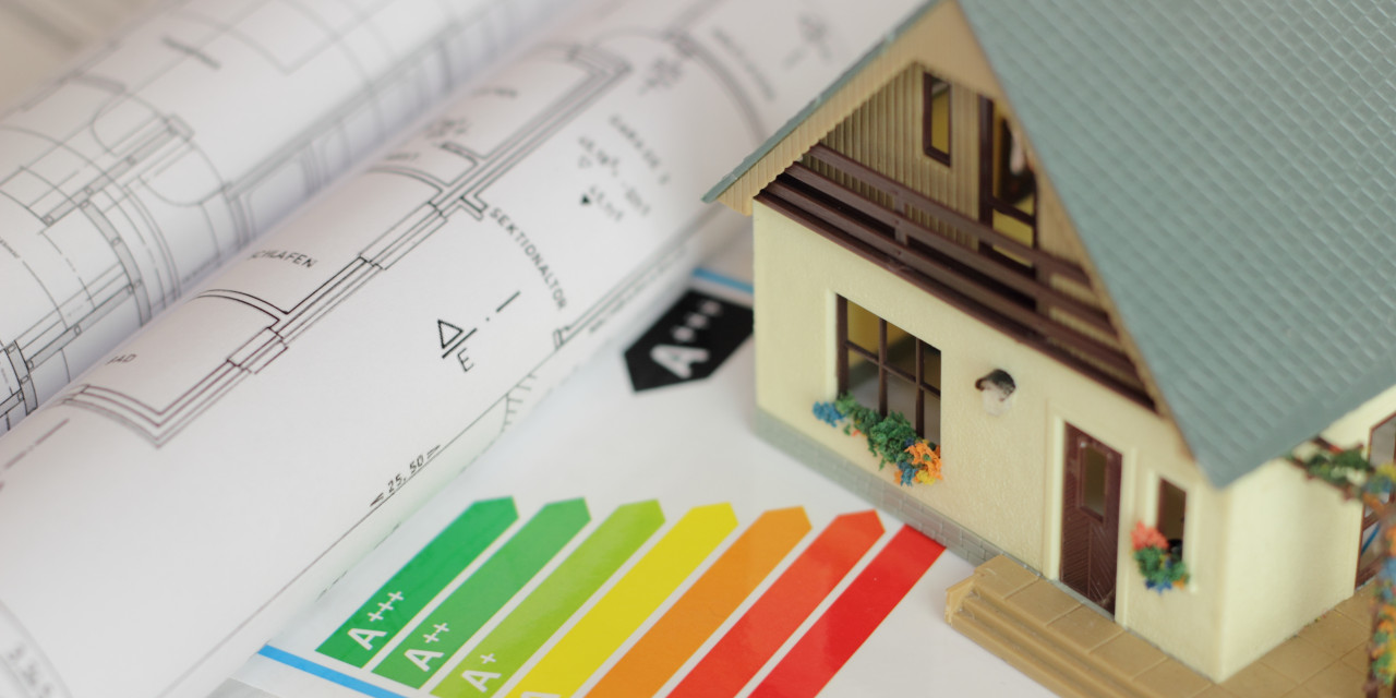 Bauplan und Energieeffizienzskala auf dem ein Modellhaus steht